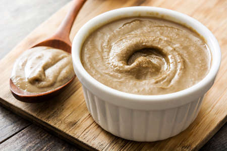 Tahini and sesame seeds on wooden table. Close upの写真素材