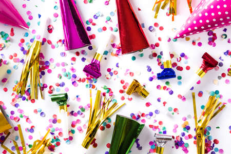 Party background. Party caps and confetti on white background. Top view.