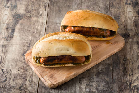 Choripan. Traditional Argentine sandwich with chorizo ??and chimichurri sauce on wooden table.の写真素材