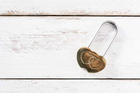 Golden padlock hearts on white wooden background. Top view. Copyspaceの写真素材