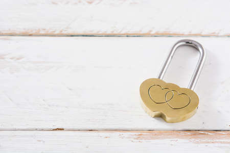Golden padlock hearts on white wooden background. Copyspace