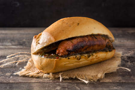Choripan. Traditional Argentina sandwich with chorizo ??and chimichurri sauce on wooden tableの写真素材
