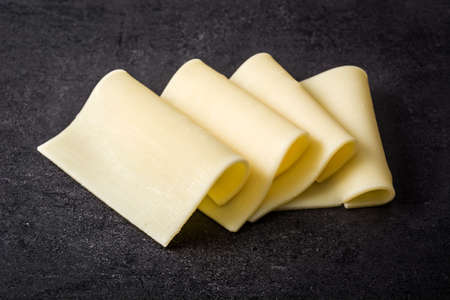 Yellow cheese slices on black slateの写真素材