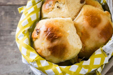Traditional Easter hot cross buns in a basket on wooden table. Close up