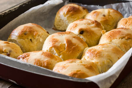 Traditional Easter hot cross buns on a wooden plate on wooden tableの写真素材