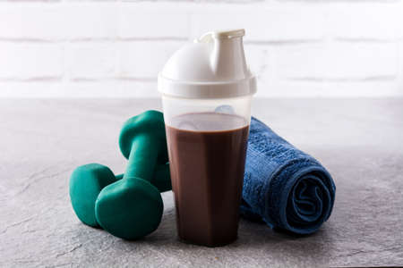 Chocolate protein shake and dumbbells on gray stoneの写真素材
