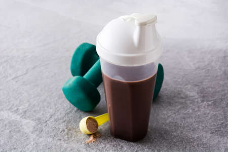 Chocolate protein shake and dumbbells on gray stoneの写真素材