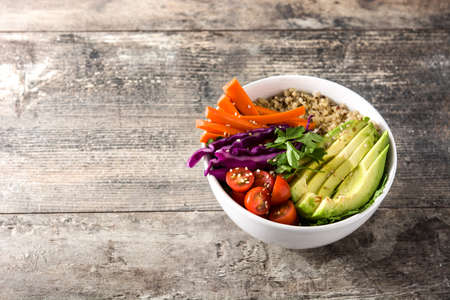 Vegan Buddha bowl with fresh raw vegetables and quinoa on wooden table. Copyspaceの写真素材
