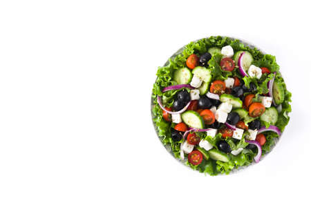 Fresh Greek salad in plate with black olive, tomato, feta cheese, cucumber and onion isolated on white background. Top view. Copyspaceの写真素材