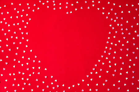 Heart shape made with heart candy on red background for Valentine's Day. Copyspace
