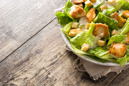 Caesar salad with lettuce, chicken and croutons on wooden table. Copyspaceの写真素材