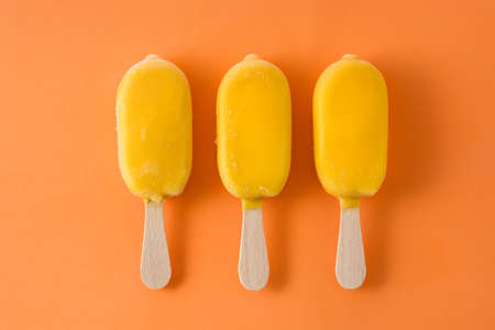 Orange ice lolly pattern on orange background. Top viewの写真素材