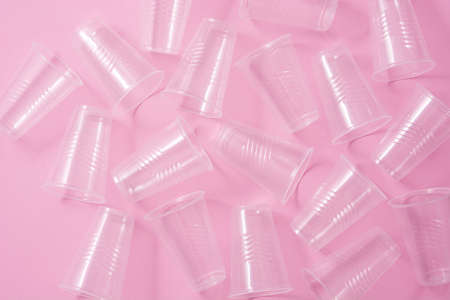 Disposable plastic glasses on pink background. Top view