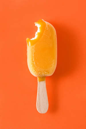 Bitten orange  ice lolly  on orange background. Top viewの写真素材