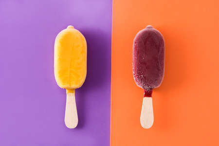 Strawberry and orange ice lolly on violet and orange background.の写真素材