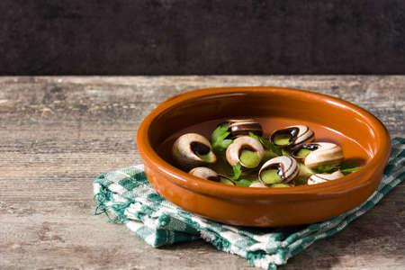 Escargots de Bourgogne in brown bowl on wooden table. Copyspaceの写真素材