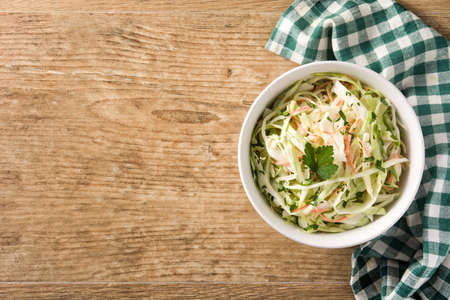 Coleslaw salad in white bowl on wooden table. Top view. Copy spaceの写真素材