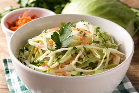 Coleslaw salad in white bowl on wooden table.の写真素材