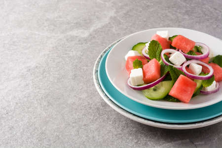 Watermelon salad with feta cheese,mint,onion and cucumber on gray backgroundの写真素材