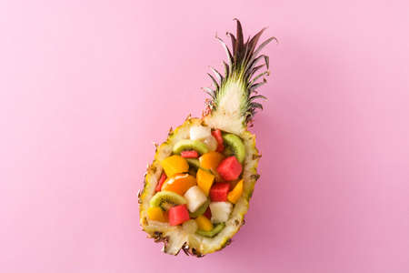 Mix fruit served inside pineapple on pink backgroundの写真素材
