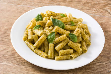 Penne pasta with pesto sauce and basil on wooden tableの写真素材