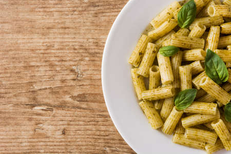 Penne pasta with pesto sauce and basil on wooden tableの写真素材