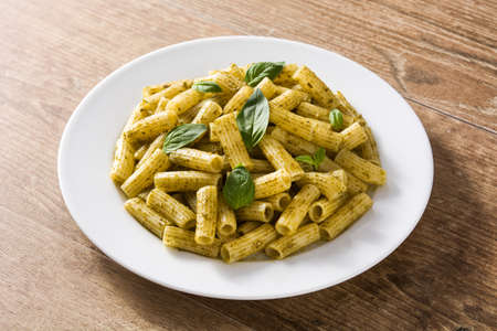 Penne pasta with pesto sauce and basil on wooden tableの写真素材