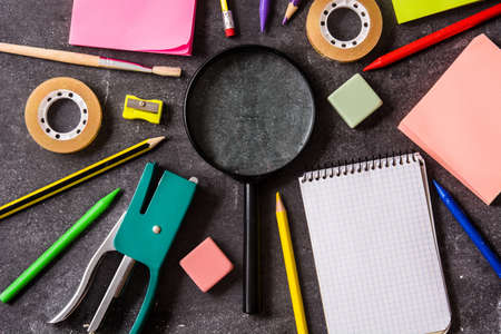 Assorted school supplies on black slate. Back to school concept.
