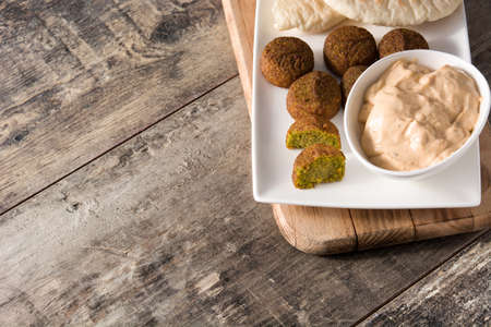 Falafel and tahini sauce one a plate on wooden table. Copyspacの写真素材