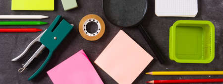 Assorted school supplies on black slate. Back to school concept. Panorama viewの写真素材