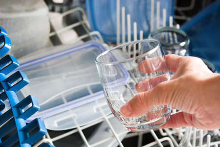 woman taking a glass out of the dishwasherの写真素材