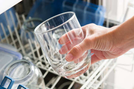 woman taking a glass out of the dishwasherの写真素材