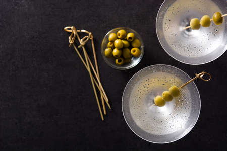 Classic Dry Martini with olives isolated on black background. Top view. Copyspace
