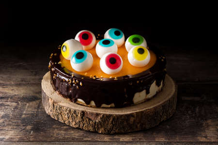 Halloween cake with candy eyes on wooden table and black background.の写真素材