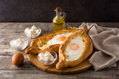 Traditional Adjarian Georgian khachapuri with cheese and egg on wooden tableの写真素材