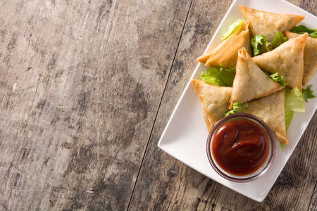 Samsa or samosas with meat and vegetables on wooden table. Traditional Indian food. Top view. Copyspaceの写真素材