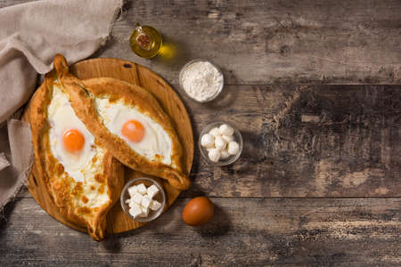 Traditional Adjarian Georgian khachapuri with cheese and egg on wooden table. Top view. Copyspace