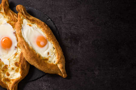 Traditional Adjarian Georgian khachapuri with cheese and egg on black background. Top view. Copyspaceの写真素材