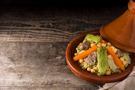 Traditional tajine with vegetables, chickpeas, meat and couscous on wooden table. Copyspaceの写真素材
