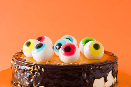 Halloween cake with candy eyes decoration on orange background. Close upの写真素材