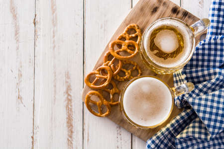 Oktoberfest beer and pretzel on white wooden table. Top view. Copyspace