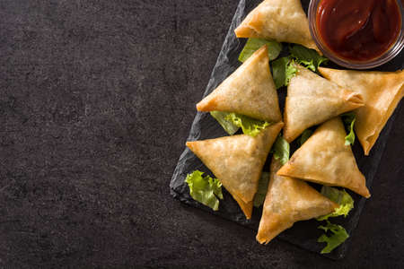 Samsa or samosas with meat and vegetables on black background. Traditional indian food. Top view. Copyspaceの写真素材