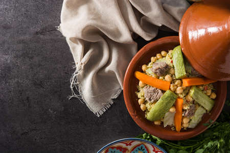 Traditional tajine with vegetables, chickpeas, meat and couscous on black slate. Top view. Copyspaceの写真素材