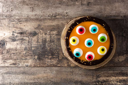 Halloween cake with candy eyes decoration on wooden table. Top view. Copy spaceの写真素材