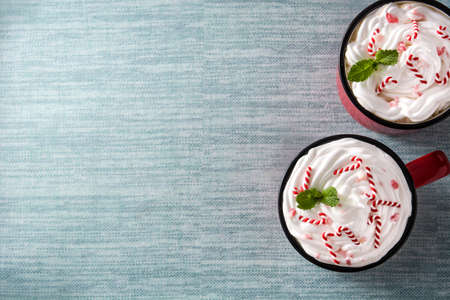 Peppermint coffee mocha decorated with candy canes for Christmas on blue background. Top view Copy...