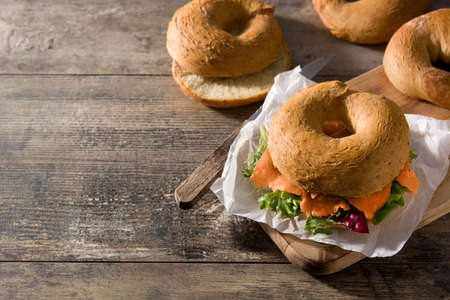Bagel sandwich with cream cheese, smoked salmon and vegetables on wooden table. Copy spaceの写真素材