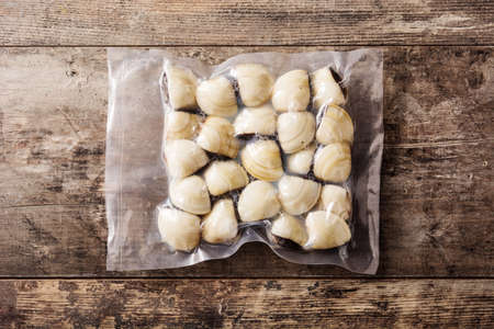 Clams packaged in plastic on wooden table. Top view