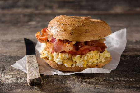 Bagel sandwich with slab bacon, egg and cheese on wooden tableの写真素材