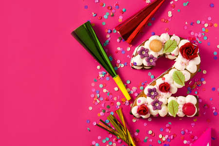 Number two cake decorated with flowers, macarons and confetti isolated on red background. Copy spaceの写真素材