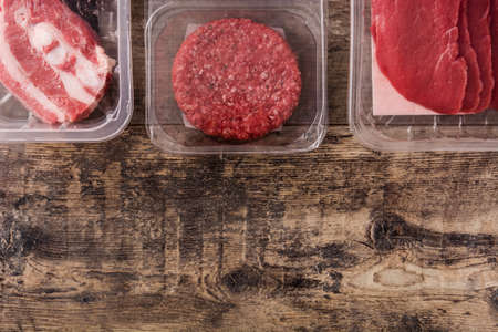 Different types of meat packaged in plastic on wooden table. Top view Copy spaceの写真素材